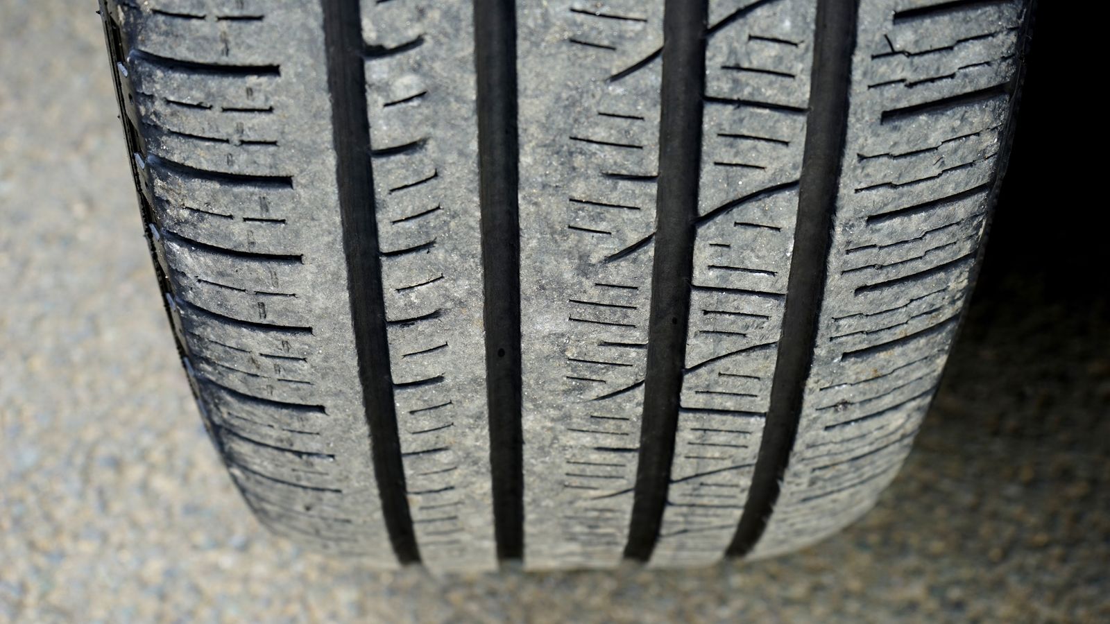 Close-up of a worn car tire tread with four deep grooves