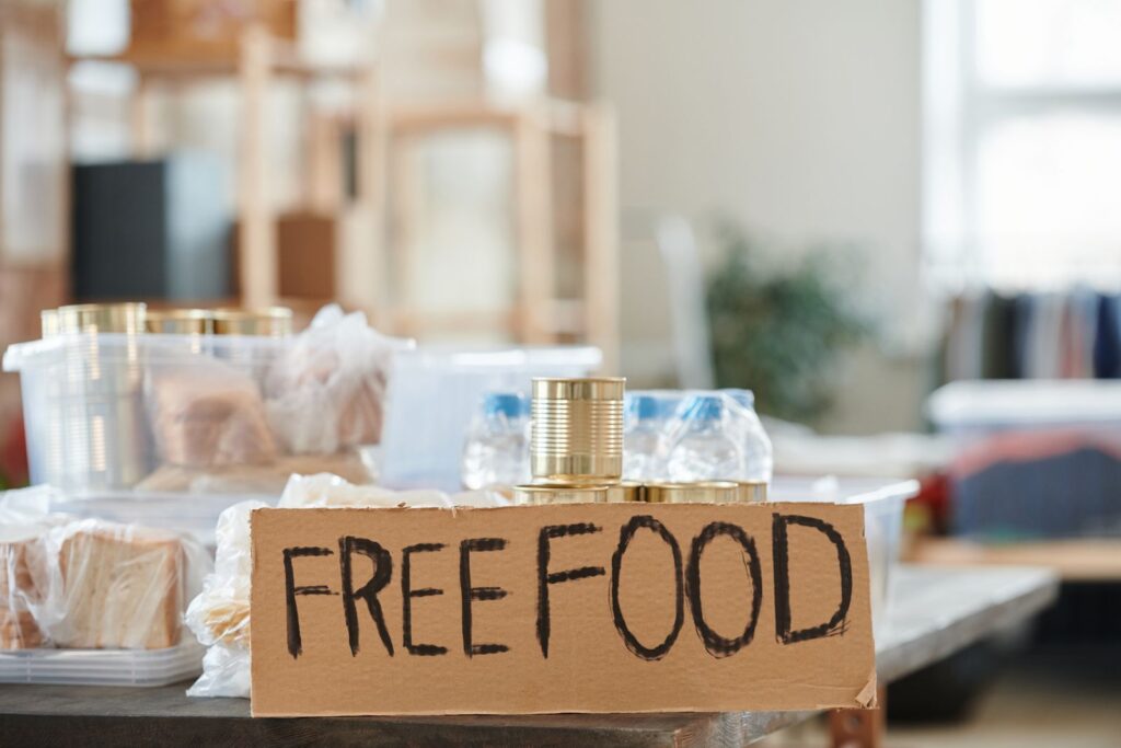 A table of bread and tins under a handwritten free food sign