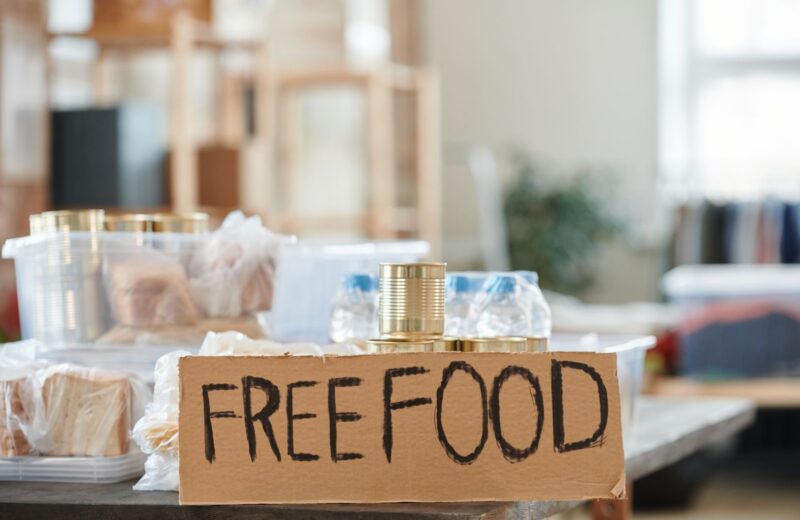 A table of bread and tins under a handwritten free food sign