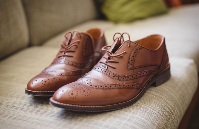 A pair of brown leather brogues with laces on a grey floor