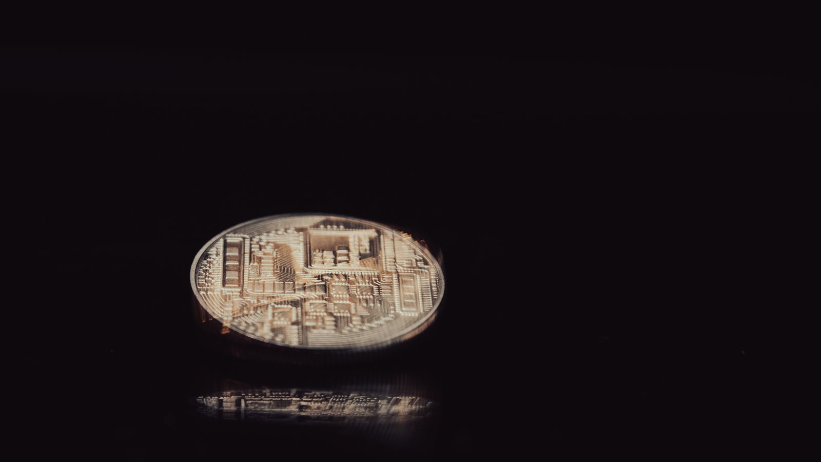A silver-coloured coin reflecting light on a black background