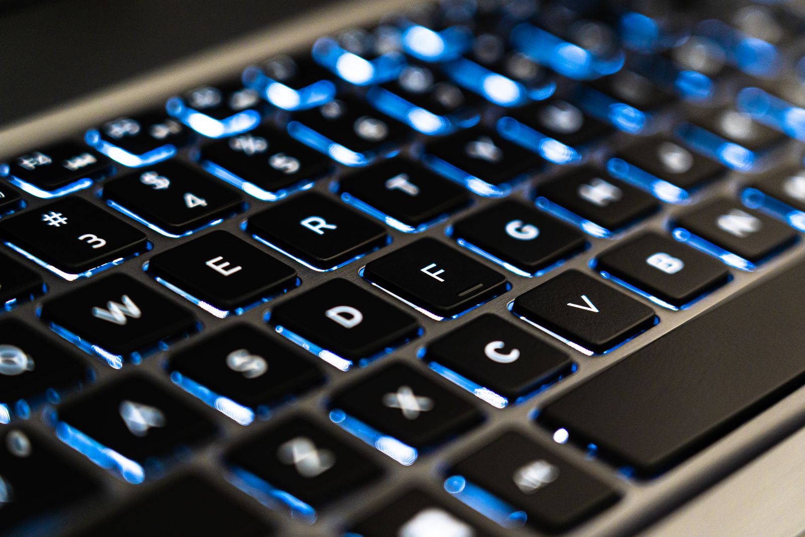 Close-up of a laptop keyboard with blue backlit keys