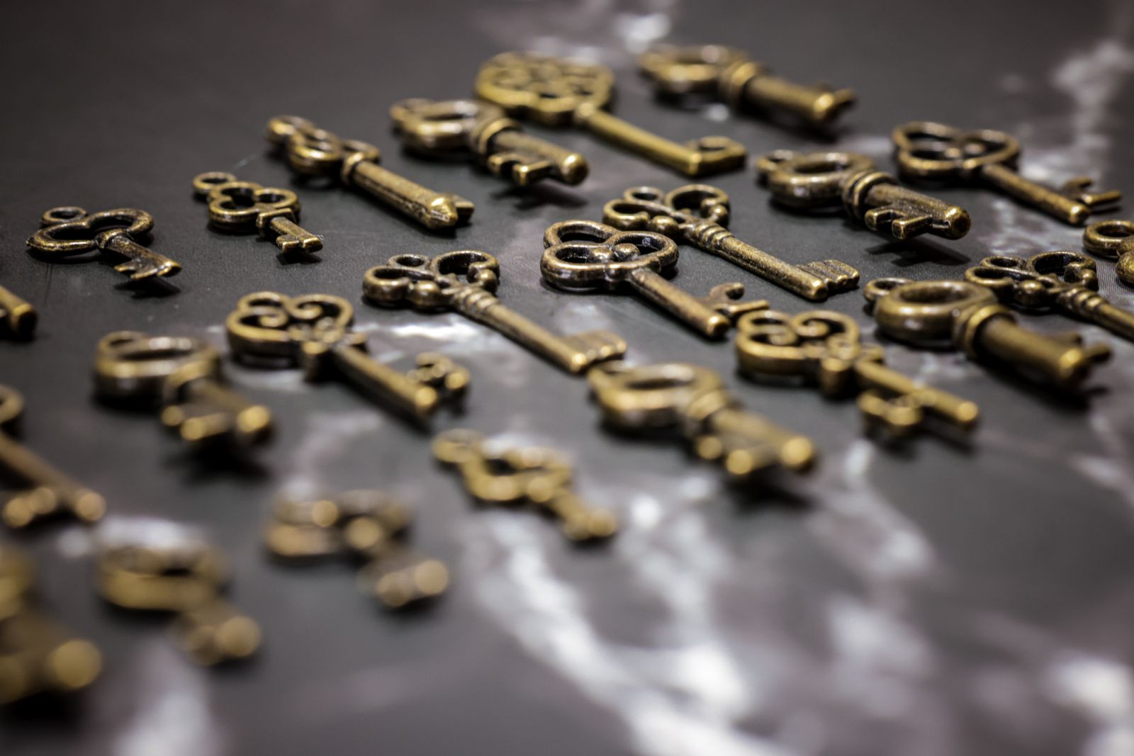 Old brass keys scattered on a dark marble surface