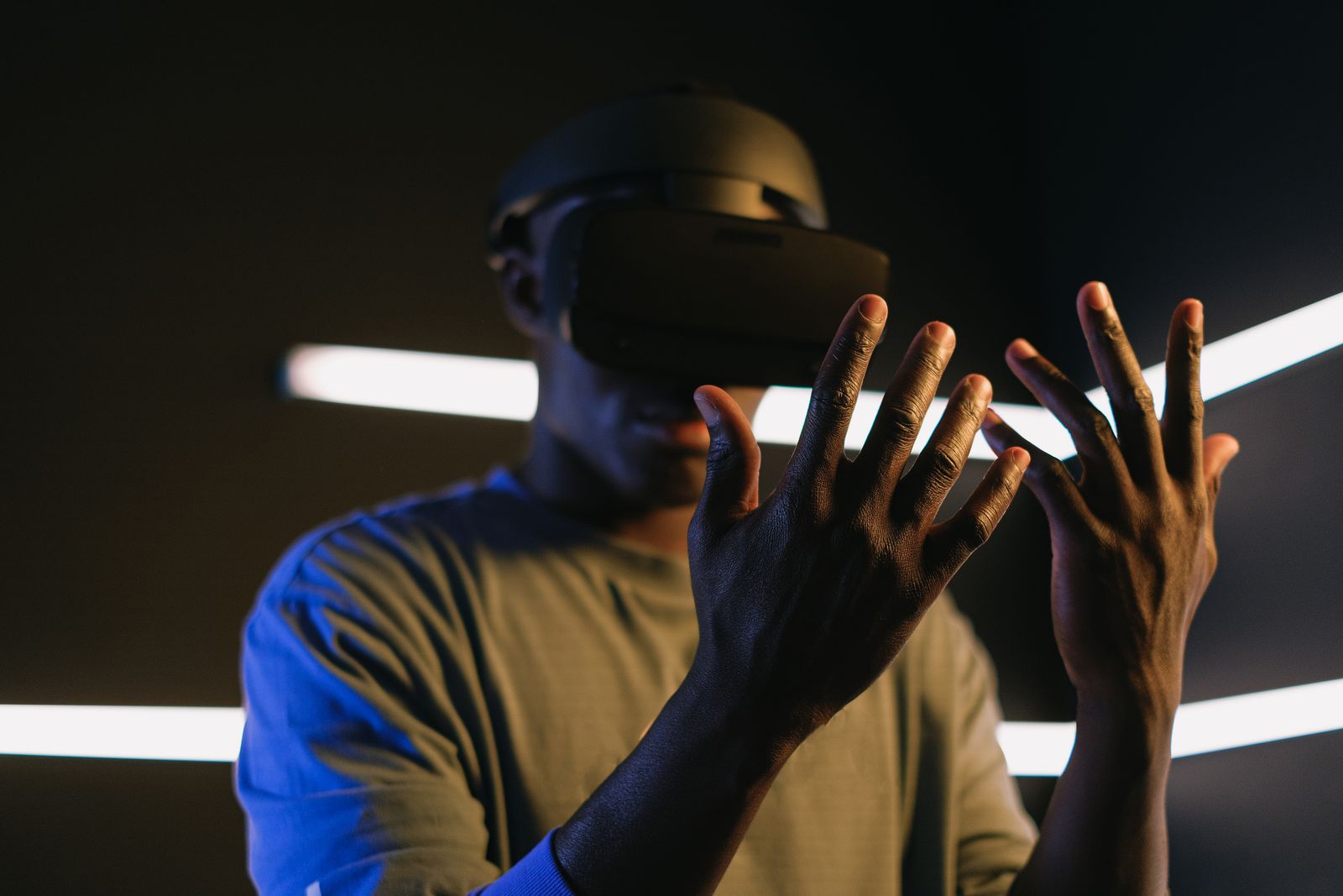 A man in a VR headset reaching out with both hands in a dark room
