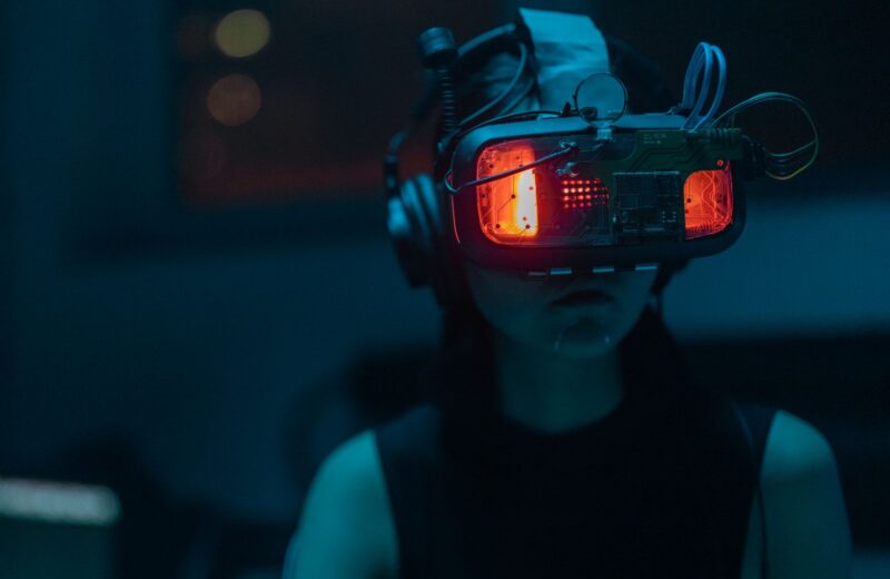 A woman wearing a VR headset in a dim teal-lit room