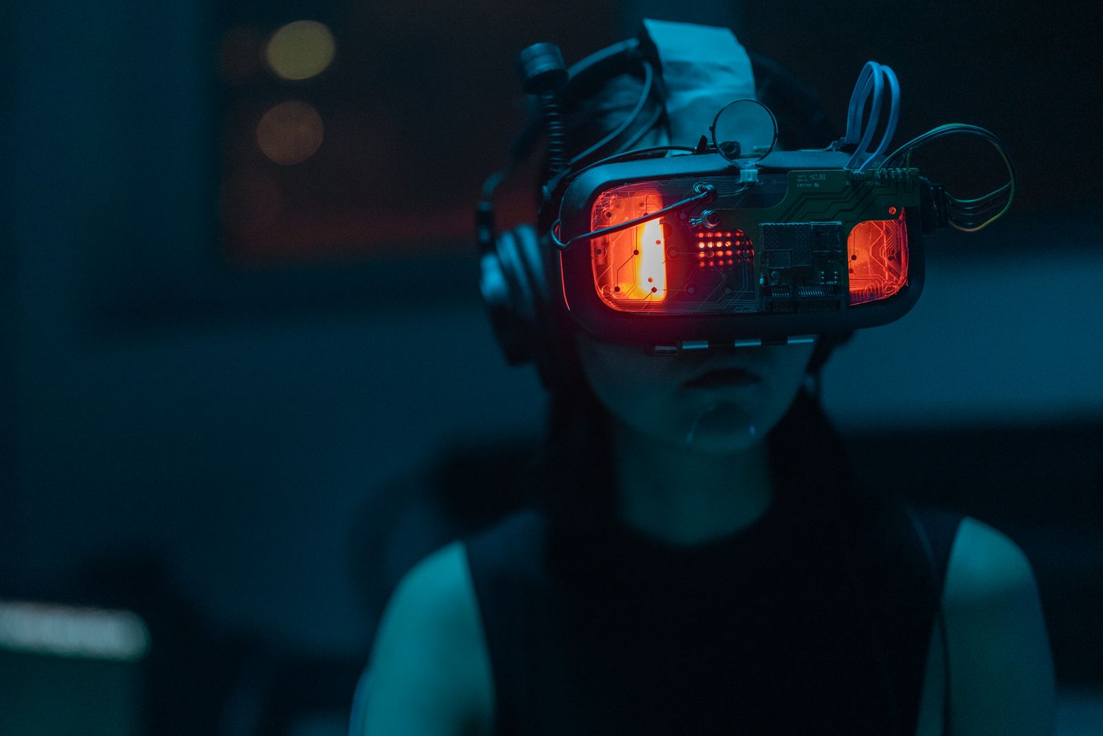A woman wearing a VR headset in a dim teal-lit room