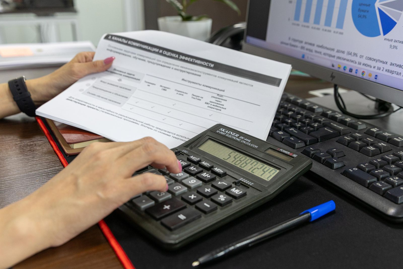 Hands working a calculator beside a printed pay report and a keyboard