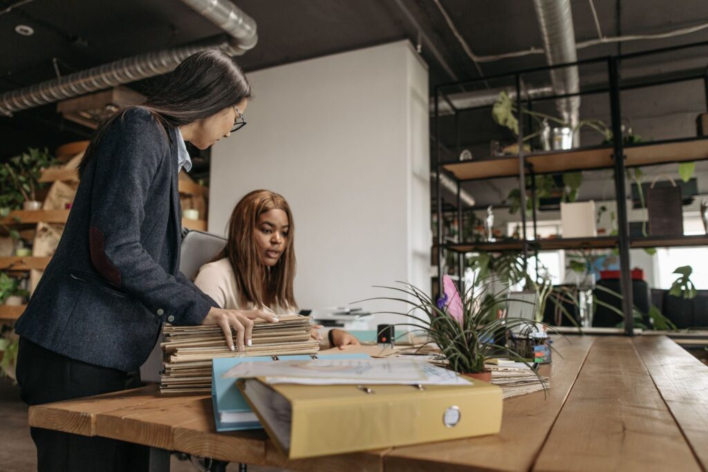 Two colleagues sorting papers and folders at a shared desk