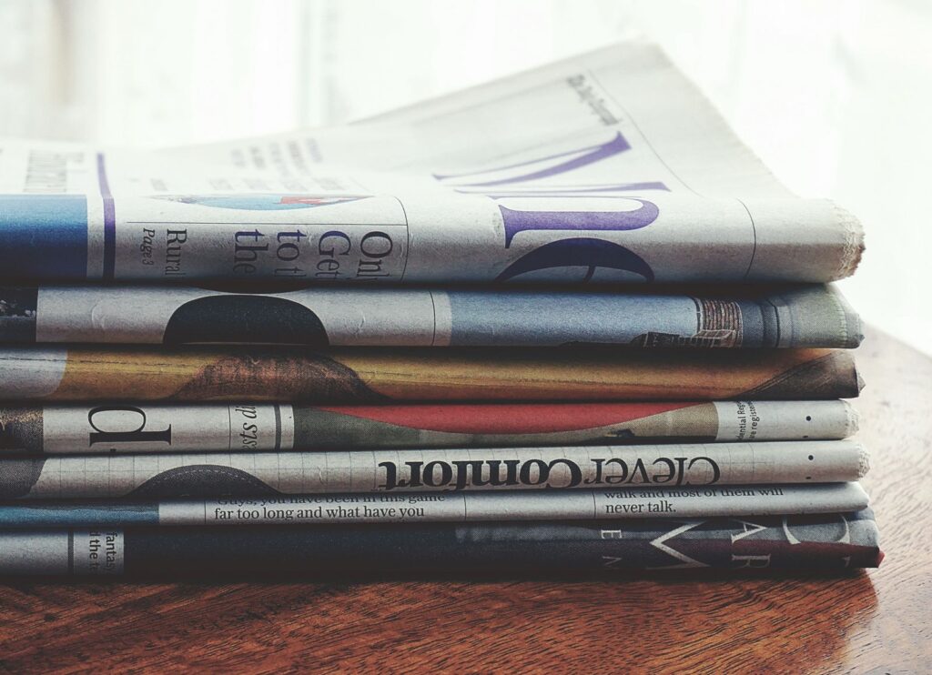 A pile of folded newspapers on a wooden table