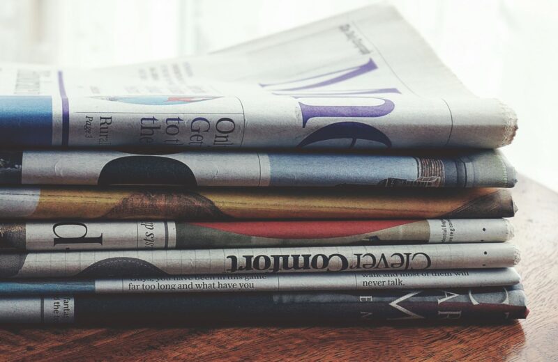 A pile of folded newspapers on a wooden table