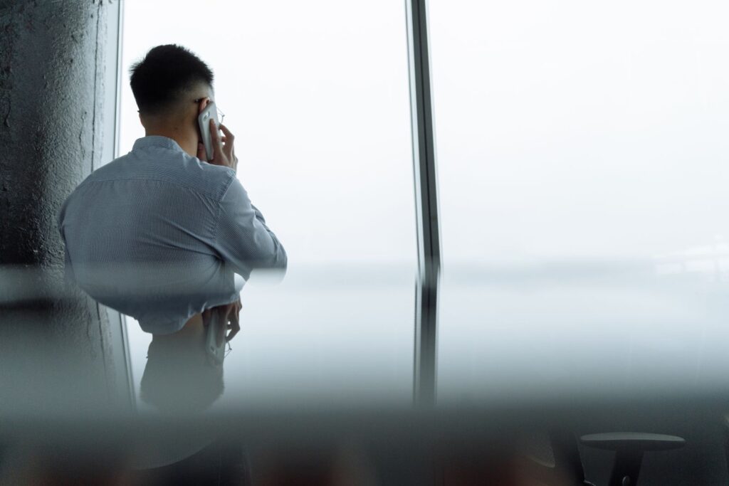 A man on a phone call by a tall office window