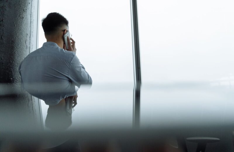 A man on a phone call by a tall office window