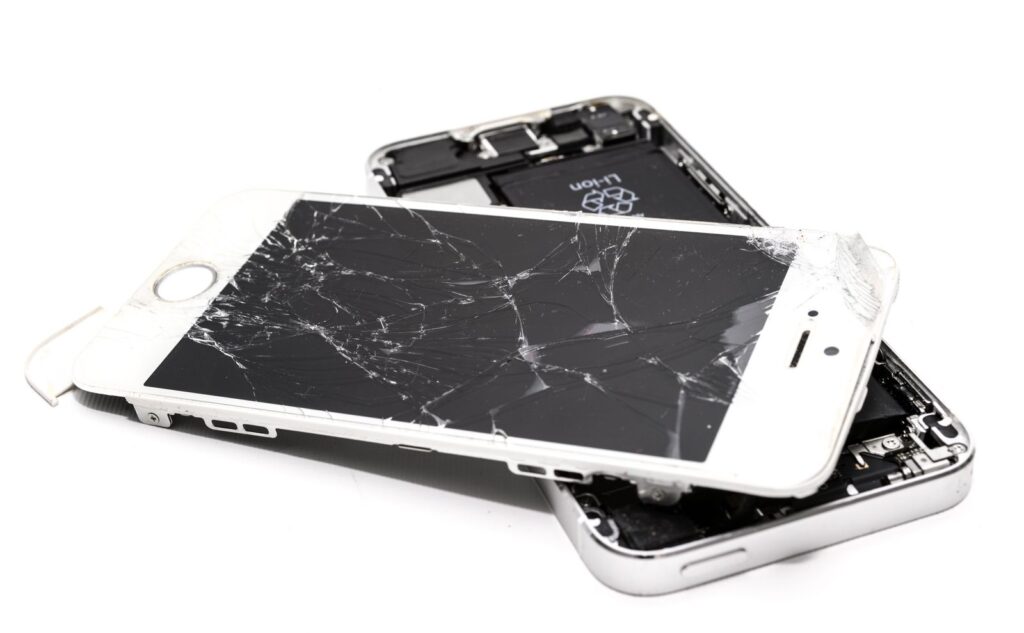 Two phones with shattered screens lying on top of each other