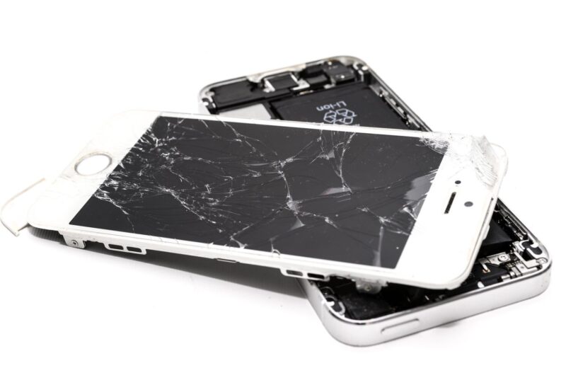 Two phones with shattered screens lying on top of each other