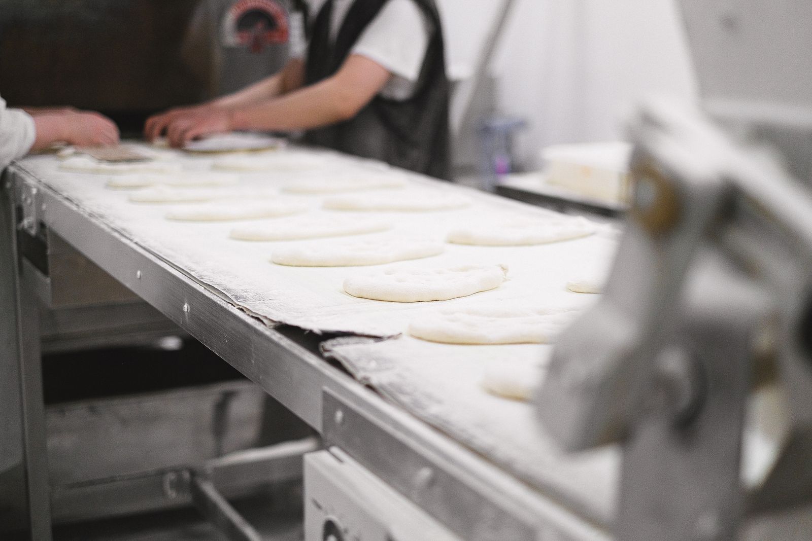 Bakery workers shaping dough on a production line