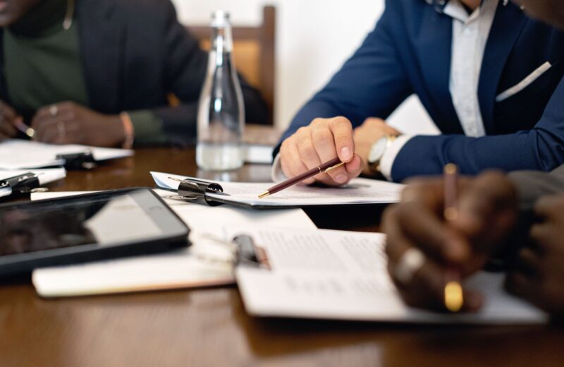 Two people signing a contract across a meeting table