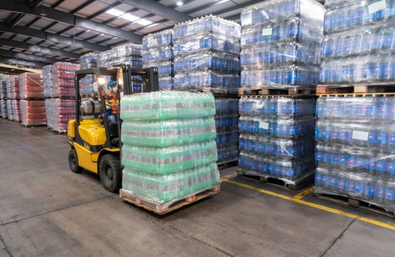 A forklift moving stacked pallets in a warehouse