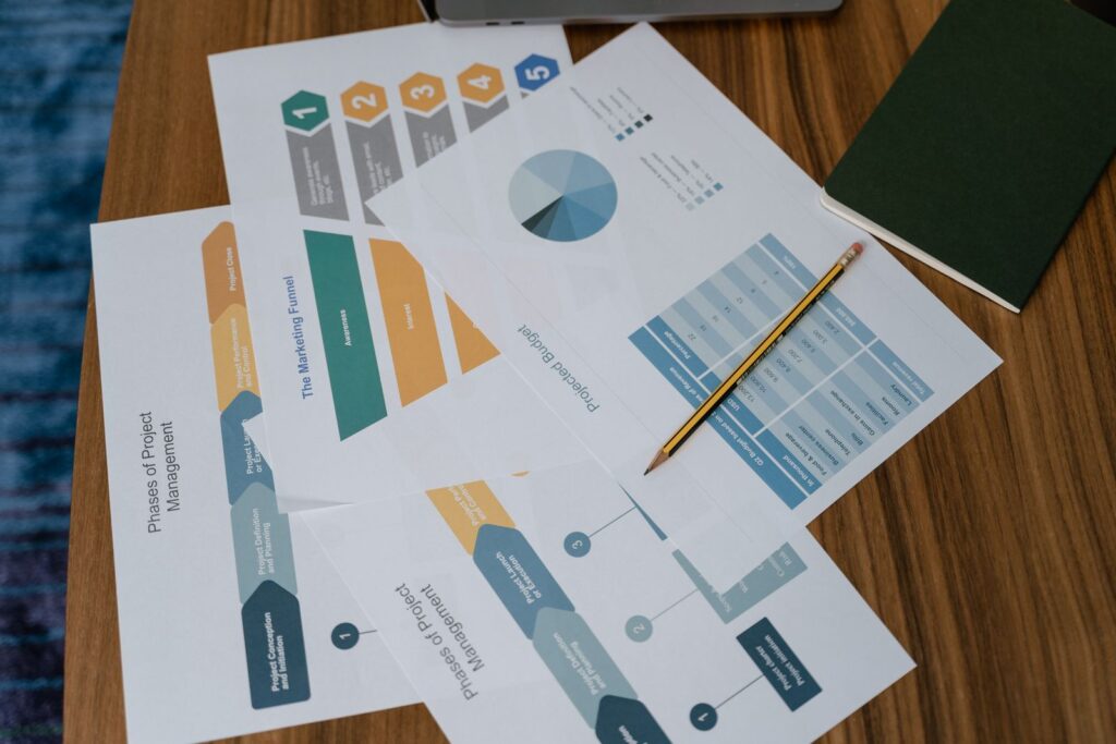 Printed charts and project documents on a desk with a pencil