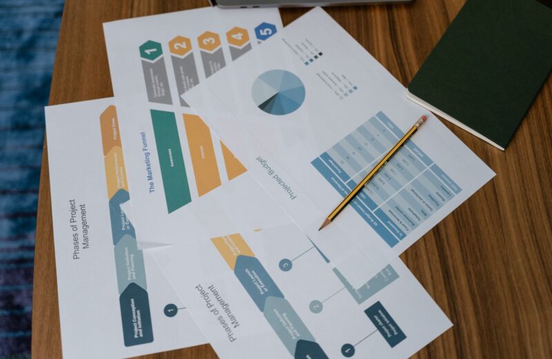 Printed charts and project documents on a desk with a pencil