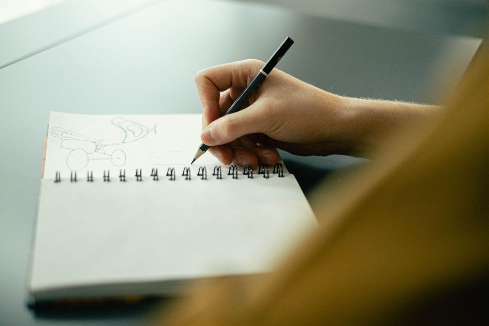 A hand sketching small thumbnails in a notebook with a pen