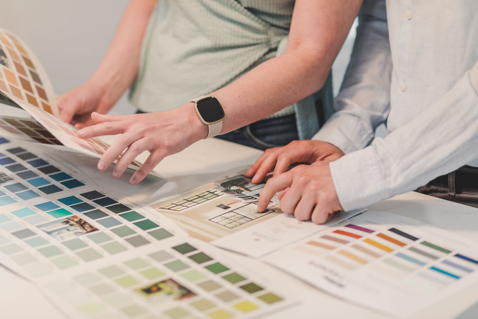 Two people choosing colours from printed palette sheets on a table