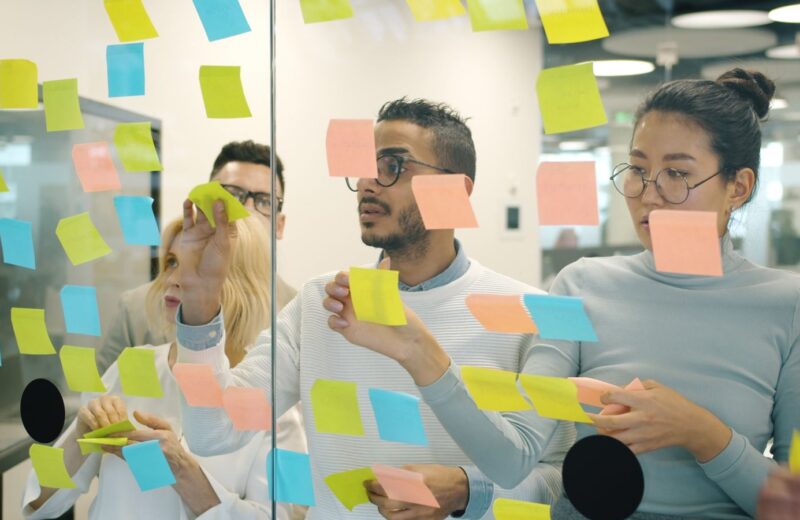 A team looking at sticky notes on a glass wall during a workshop