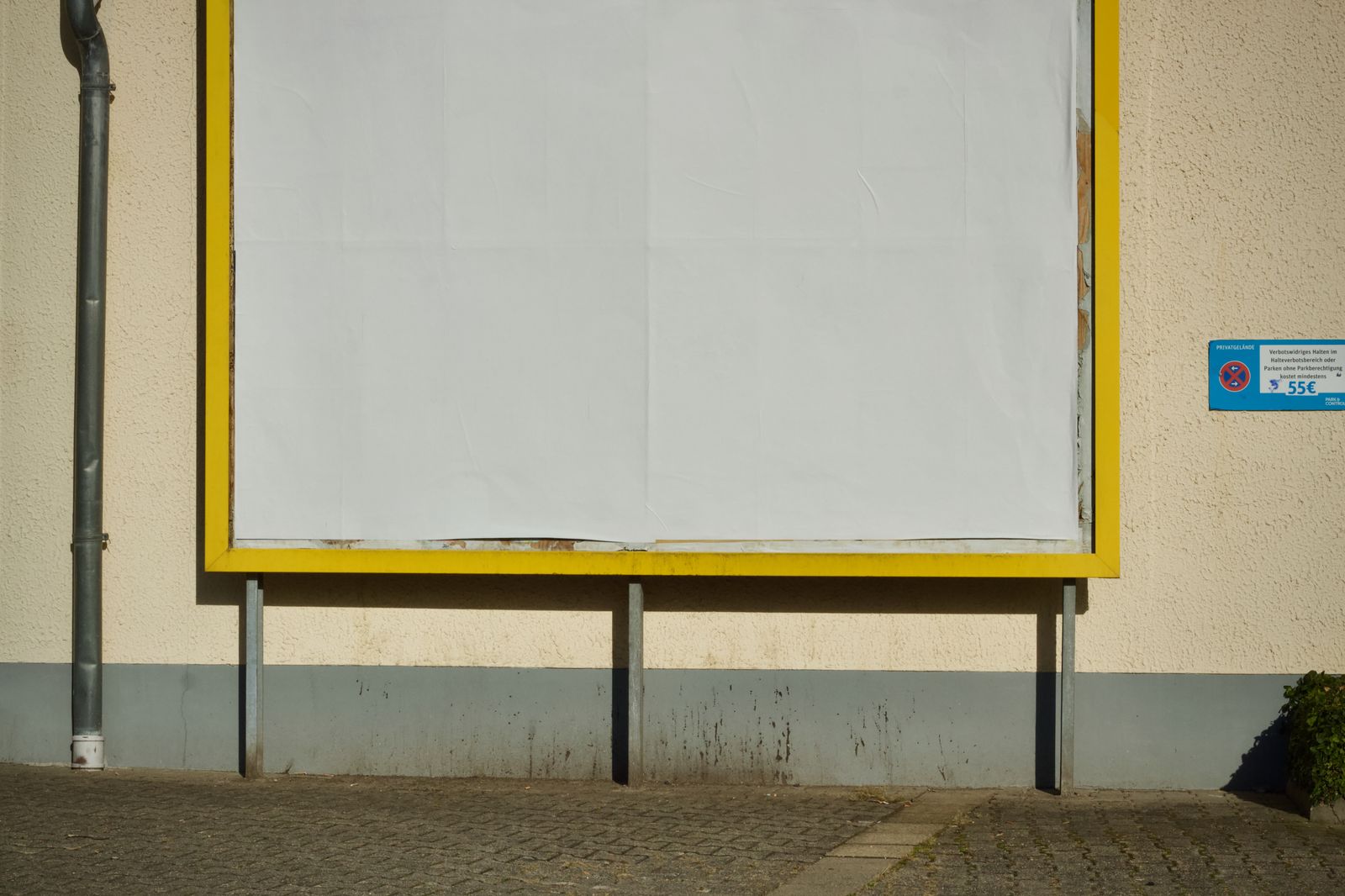 A blank billboard with a yellow frame on a sunny street
