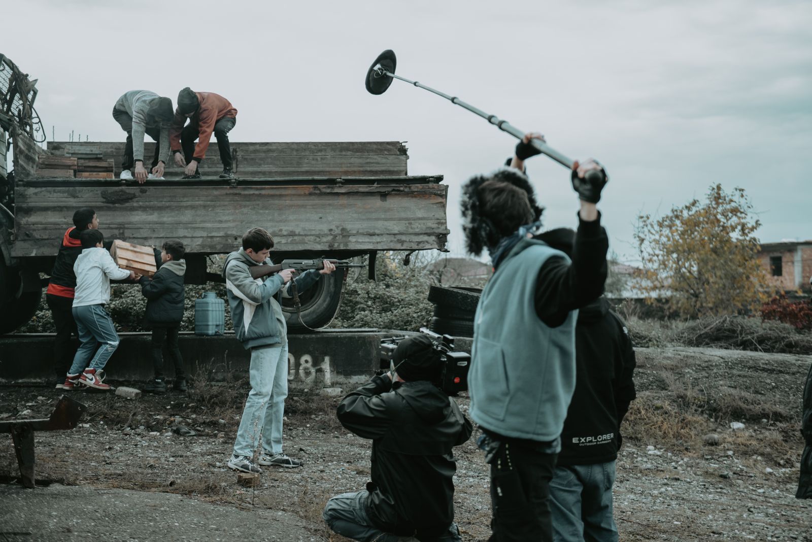A small film crew with a camera and a boom microphone on an outdoor set