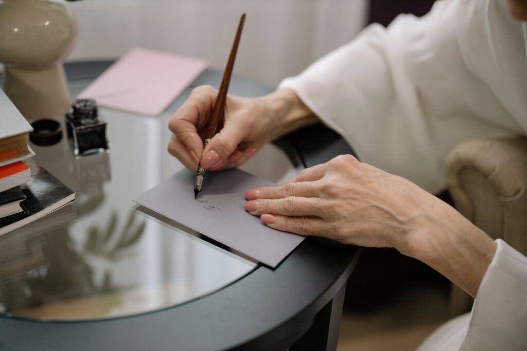 A hand writing on a grey envelope with a fountain pen