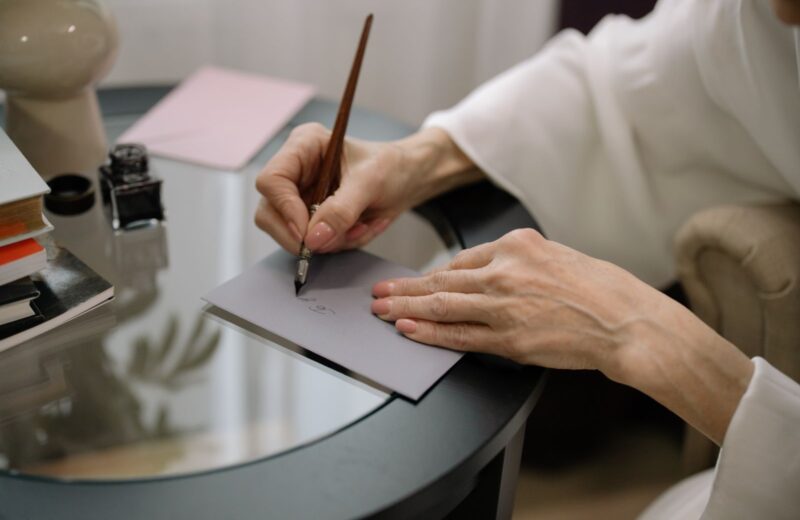 A hand writing on a grey envelope with a fountain pen