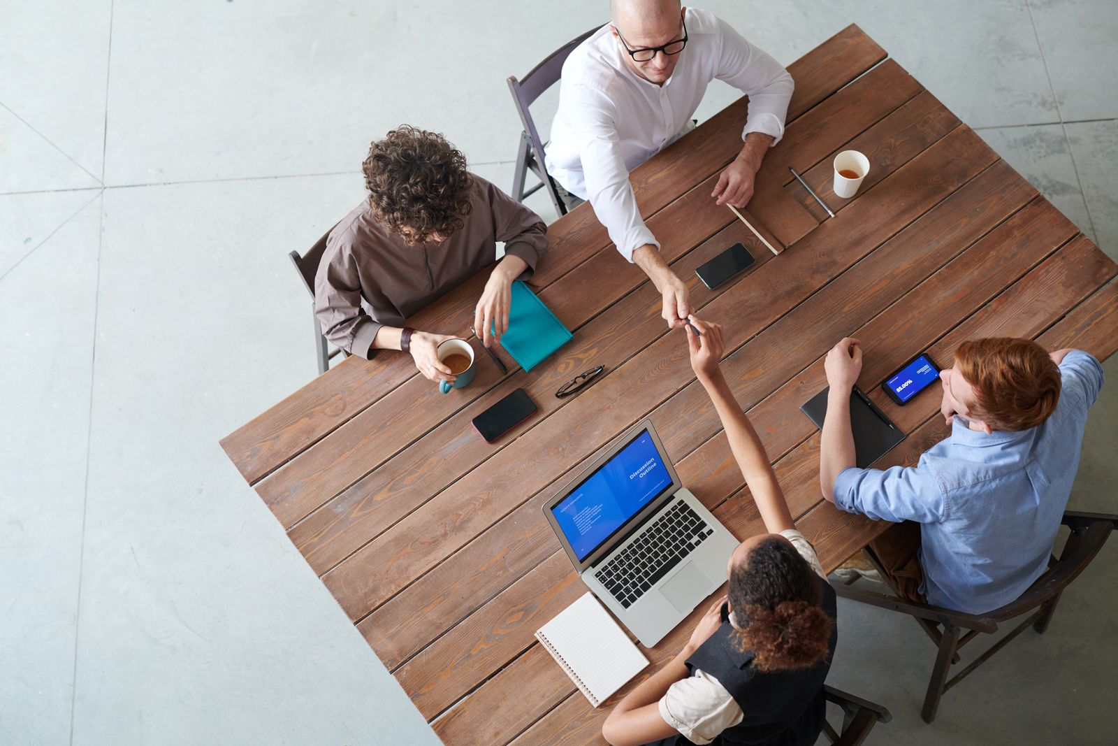 Seen from above, four people working on laptops around a wooden table