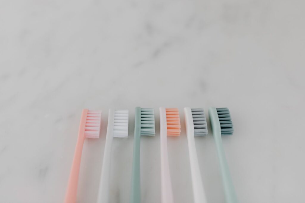A row of pastel toothbrushes lying on a marble surface