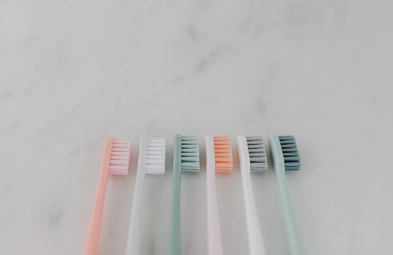 A row of pastel toothbrushes lying on a marble surface