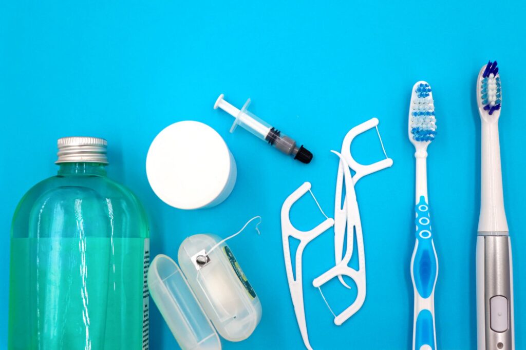 Toothbrushes, floss picks and mouthwash laid out on a blue surface