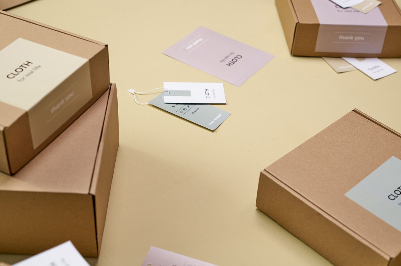 Plain cardboard boxes with paper labels on a yellow surface