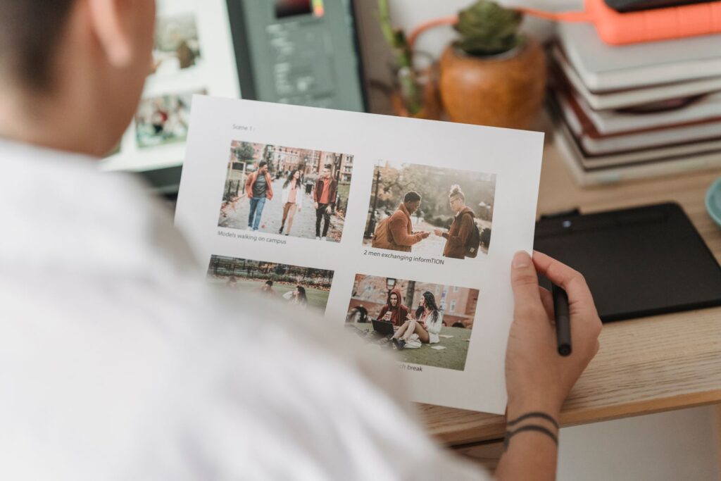 A designer checking a printed photo layout at a desk