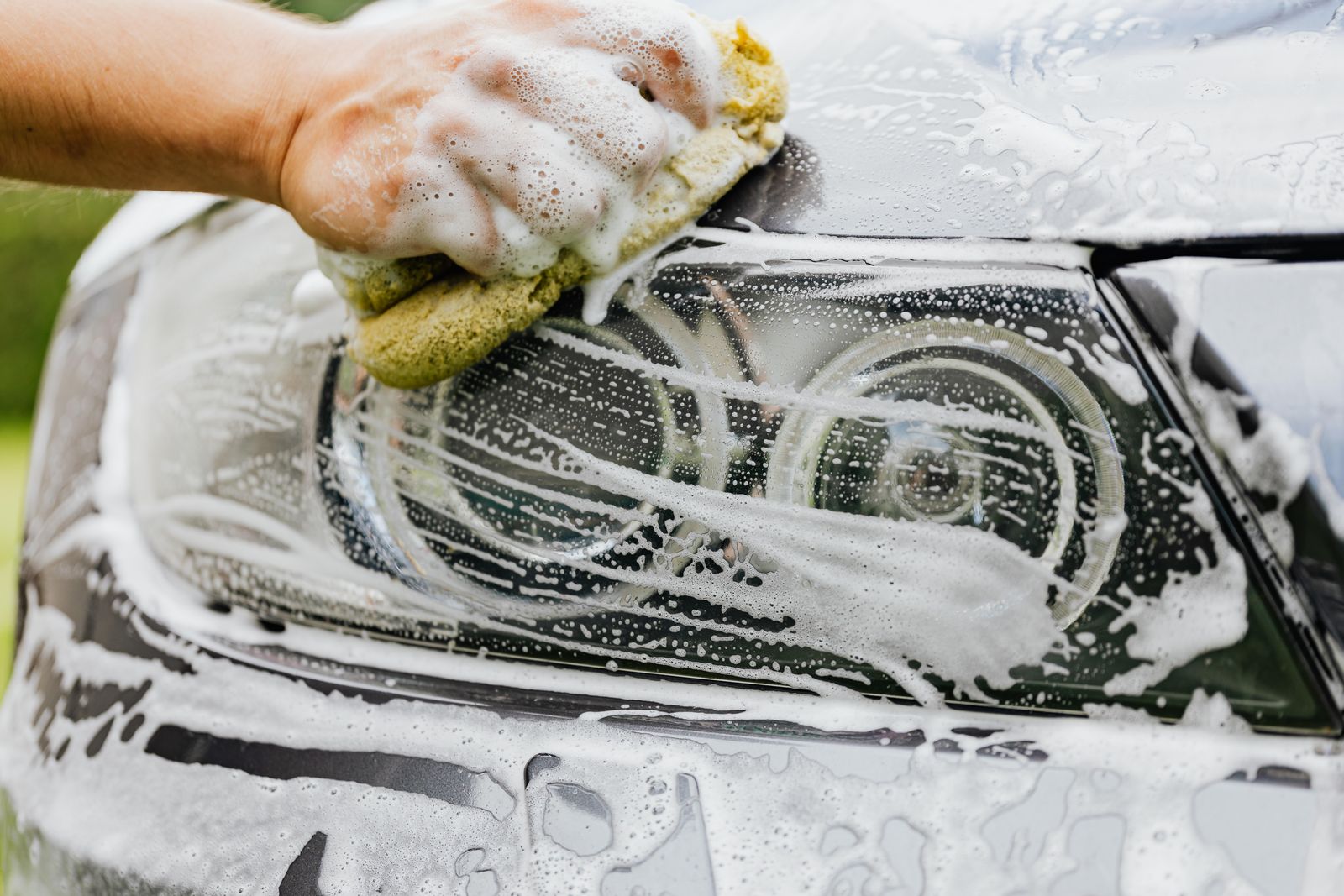 A soapy wash sponge on a headlight during a hand wash