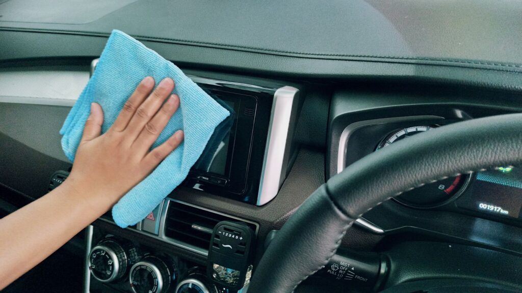 A blue microfibre cloth wiping a car dashboard