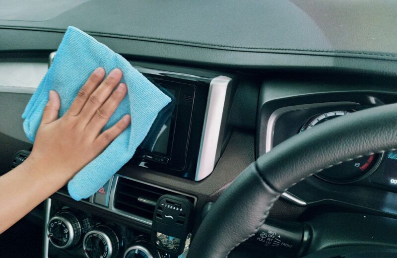 A blue microfibre cloth wiping a car dashboard