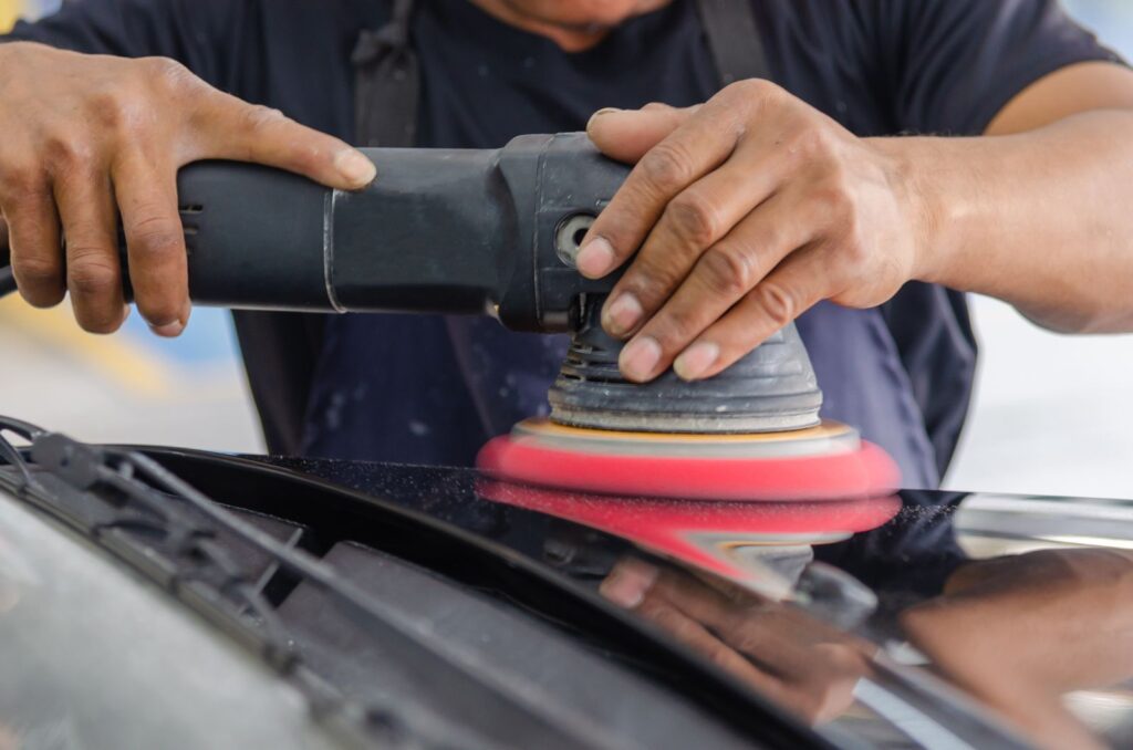 Machine polishing a dark panel with a red foam pad