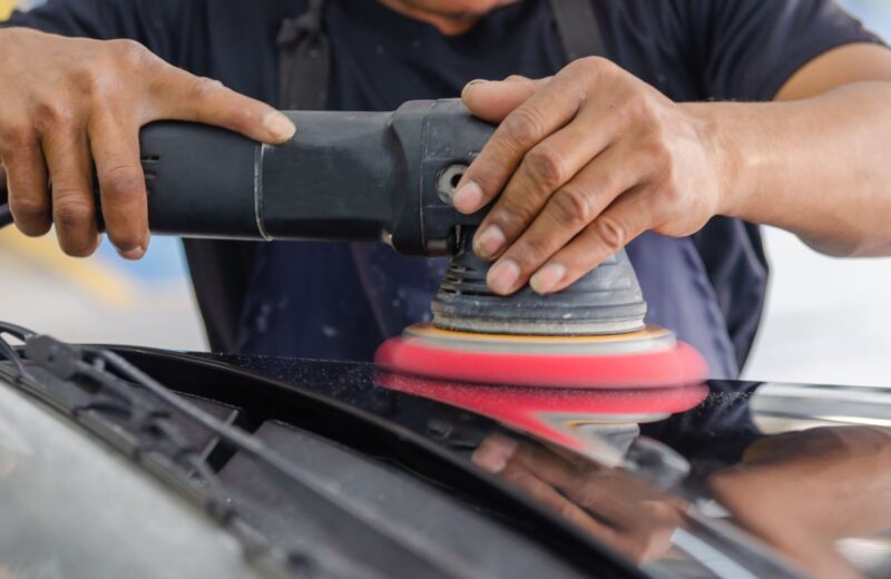 Machine polishing a dark panel with a red foam pad