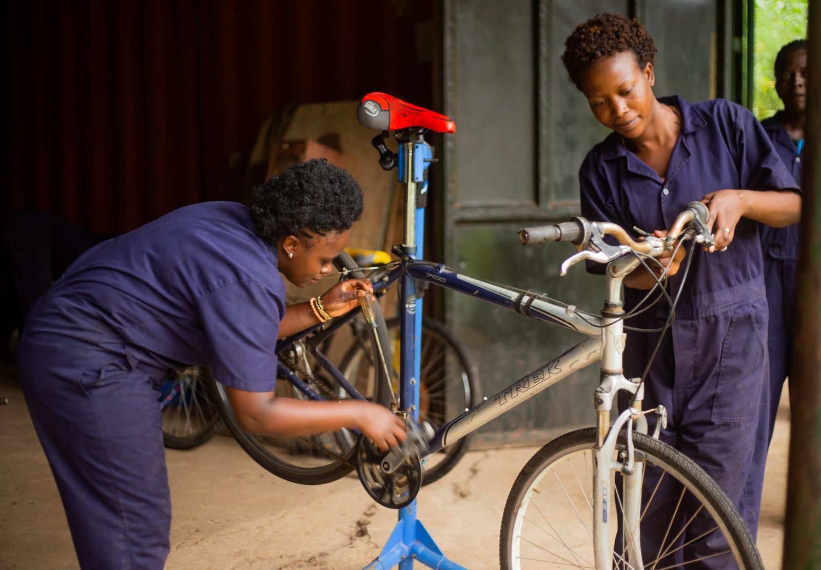 Two mechanics in overalls servicing a bicycle in a repair workshop