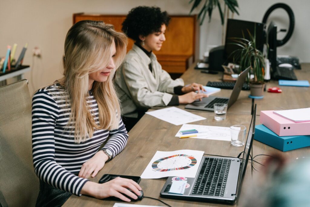 Two colleagues comparing figures on their laptops in an office