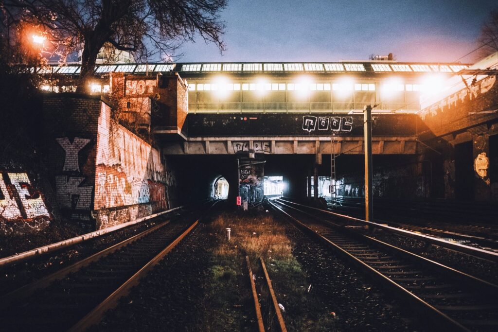 Railway tracks running under a lit bridge at night