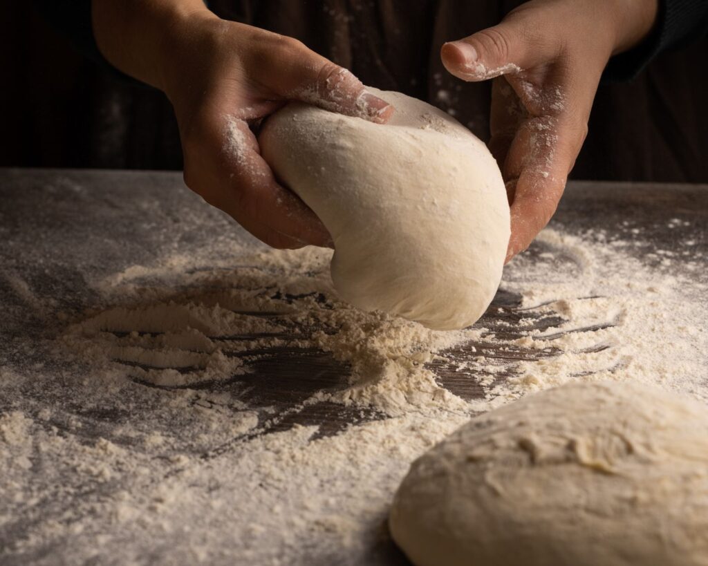 Hands kneading dough on a floured worktop