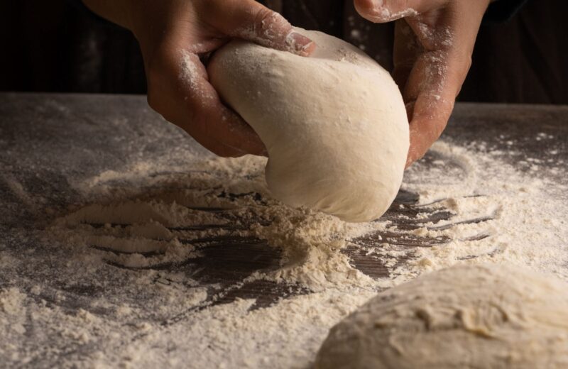 Hands kneading dough on a floured worktop