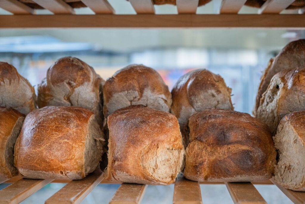 A crusty sourdough loaf on a wooden shelf