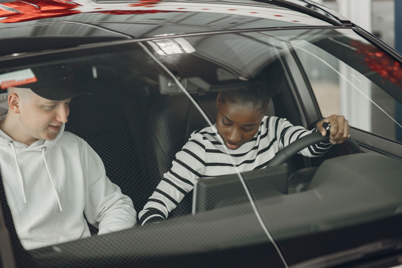 A driving instructor in the passenger seat talking a learner through the controls of a car