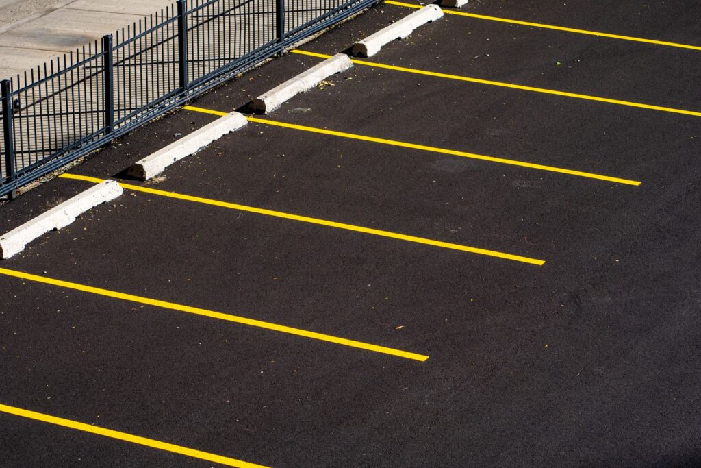 An empty car park seen from above with yellow bay lines on dark asphalt