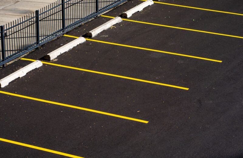 An empty car park seen from above with yellow bay lines on dark asphalt
